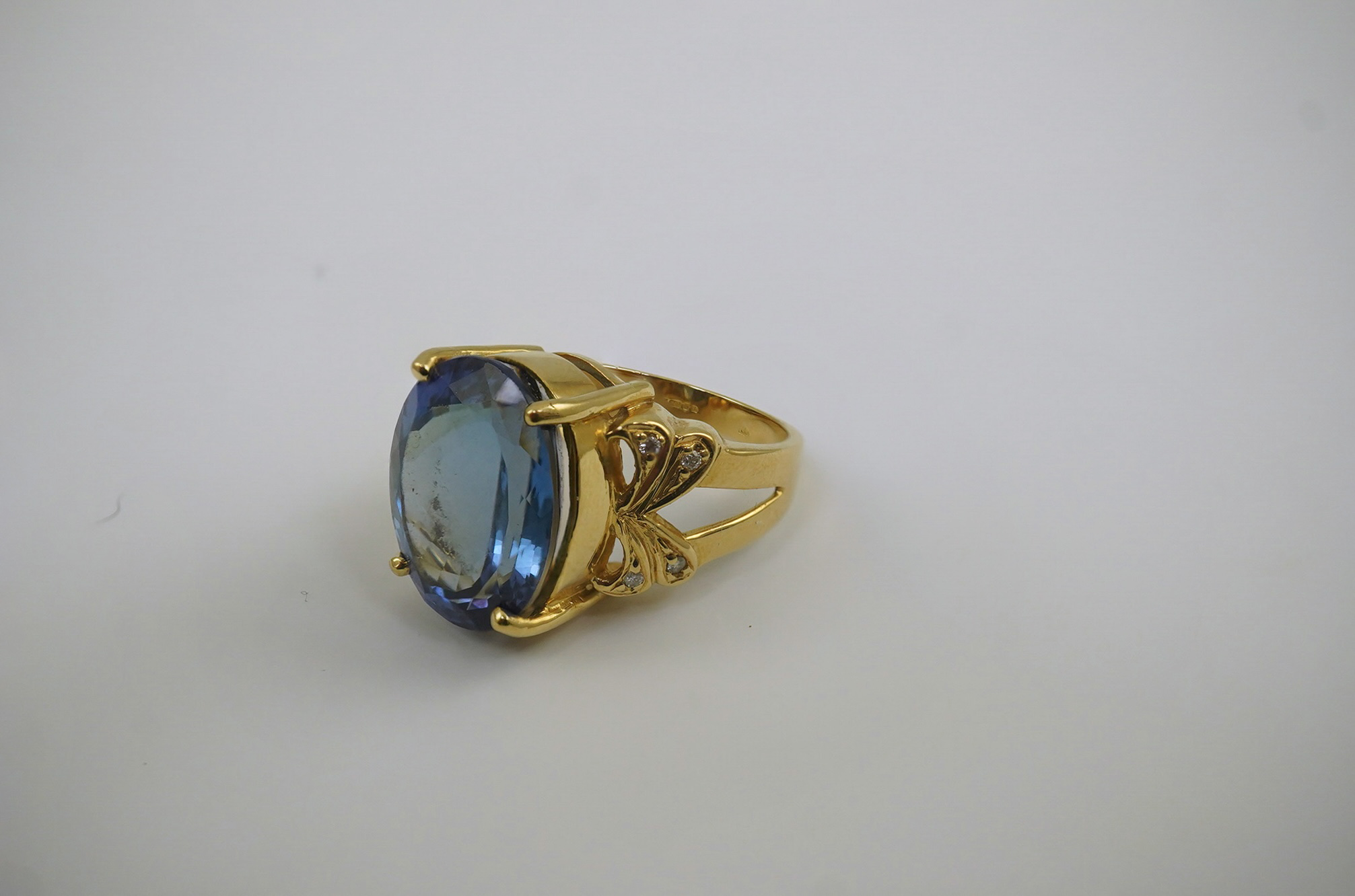 A modern 18ct gold and single stone oval cut tanzanite set dress ring, with eight stone diamond chip set shoulders